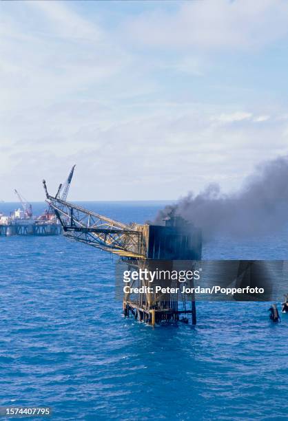 Smoke rises from the remains of the destroyed Piper Alpha module A oil platform after two explosions went off on the rig over the Piper Oilfield in...