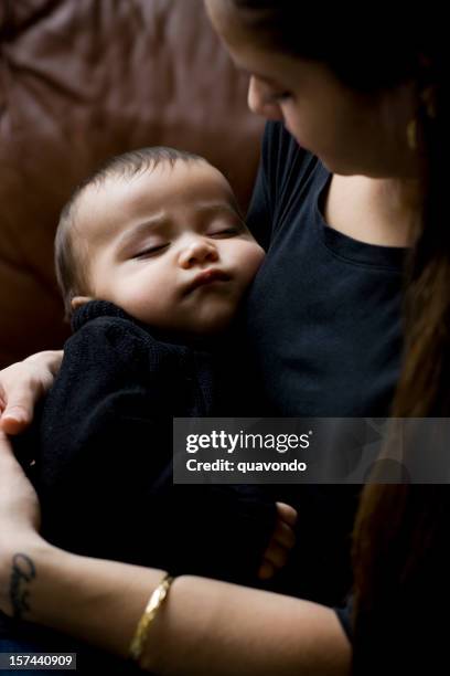 adorable hispanic baby boy sleeping in arms of mother - teen pregnancy stock pictures, royalty-free photos & images