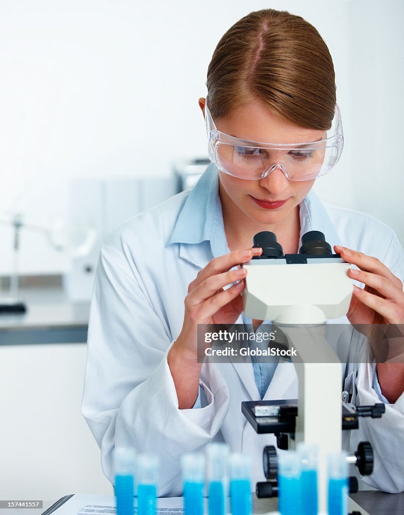 Female researcher looking into microscope