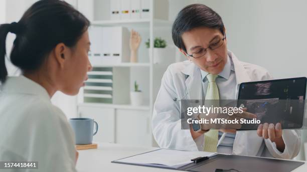 adult asian male doctors showing lung x-ray test results by tablet and describe to female patient in hospital. medical health care. - orthopedic surgery stock pictures, royalty-free photos & images