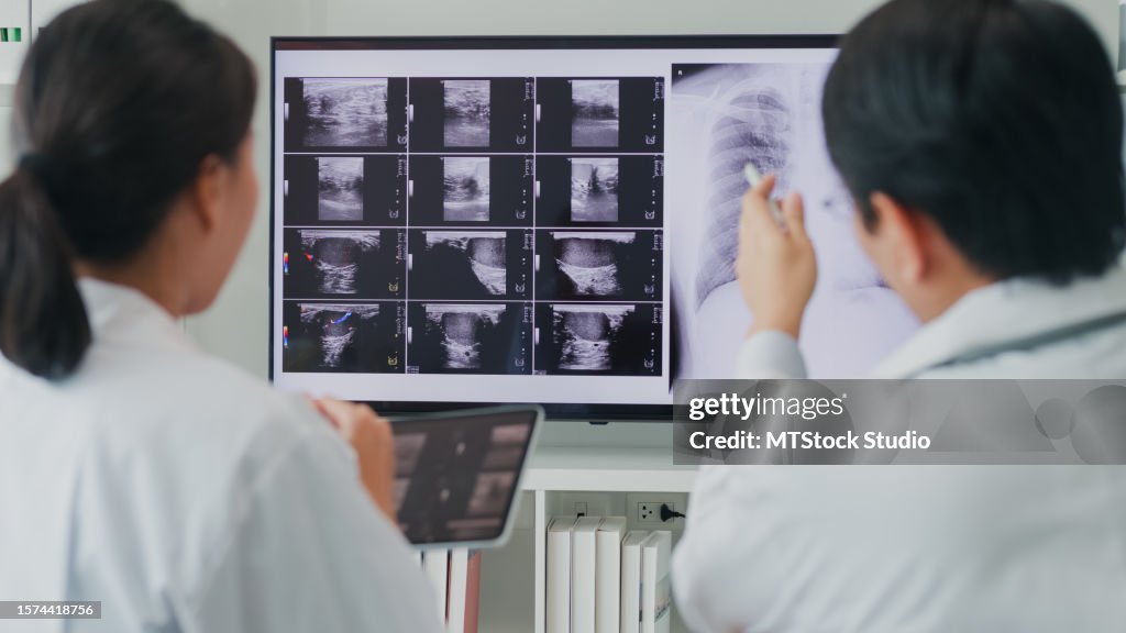 Equipo médico asiático y médico médico comprobación de la imagen de rayos X del paciente en la computadora discutiendo el resultado de la reunión en el hospital. Atención médica de salud.