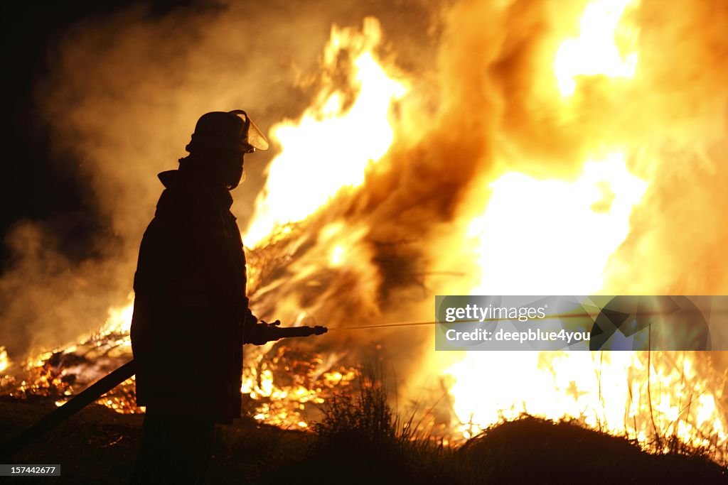 Firefighter Holding Hose Pointing Water Stream onto Fire