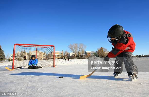 jovem caucasiana crianças brincando na pista de hóquei no gelo ao ar livre - ice hockey stick - fotografias e filmes do acervo