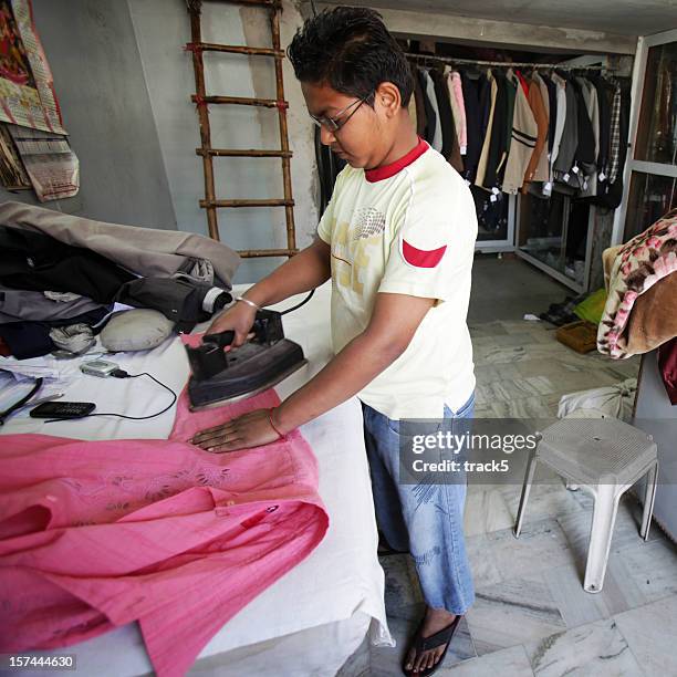 indian workers: ironing clothes - child labor stockfoto's en -beelden
