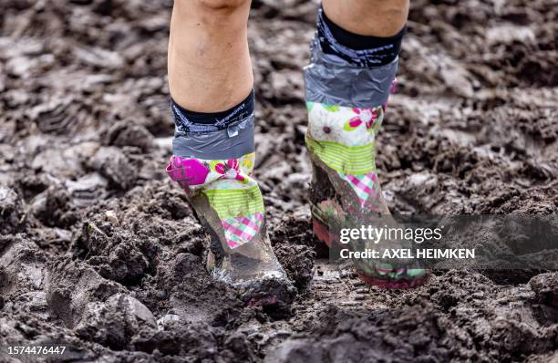 Close-up on the shoes of festival-goers wading through the mud on the grounds of the Wacken Open Air music festival on August 3, 2023 in Wacken,...