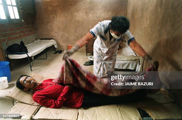 Nurse covers the dead body of Rigo, a 28-year-old male prostitute after he died from AIDS, 25 June 1993 in Lima. Rigo spent four years in this small...