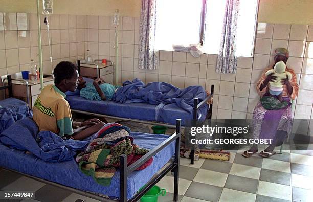 Woman plays with her child beside her husband's bed 10 December 2001 in a room of Notre Dame de Fatima solidarity and reception center in...