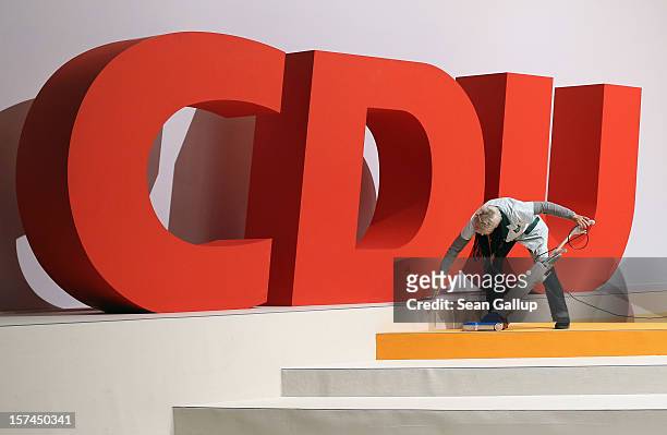 Cleaning lady vacuums next to the logo of the German Christian Democratic Union while preparing for the CDU federal party convention on December 3,...