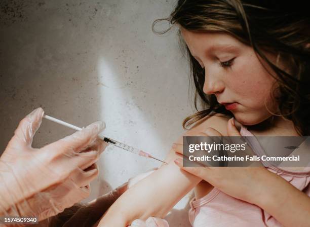 a little girl bravely accepts an injection in her arm - virus prevention stock pictures, royalty-free photos & images