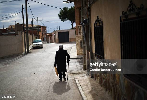 An elderly woman walks the street carrying a loaf of bread on November 30, 2012 in Villacanas, Spain. During the boom years, where in its peak Spain...