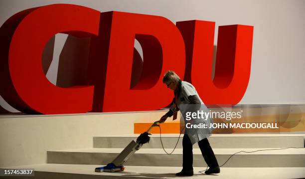 Woman cleans the carpet in front of a party logo as preparations are under way for the upcoming congress of the ruling conservative Christian...