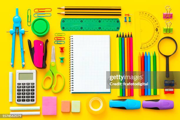 útiles escolares multicolores filmados sobre fondo amarillo - material escolar fotografías e imágenes de stock