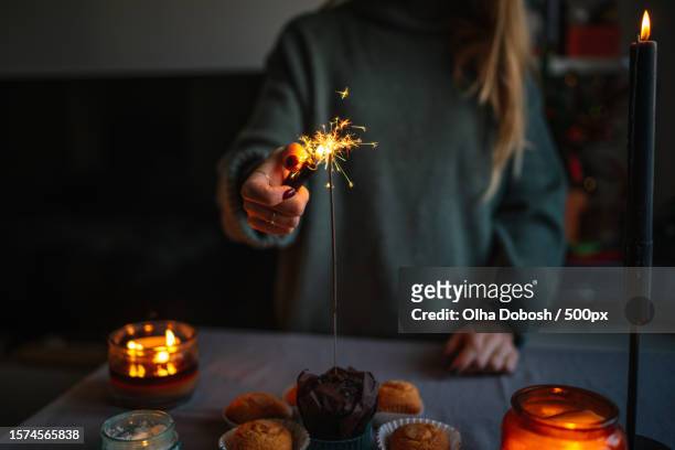 close-up of woman holding lighter to spark sparklers for cupcakes at home in dark room,spain - lighter spark stock pictures, royalty-free photos & images