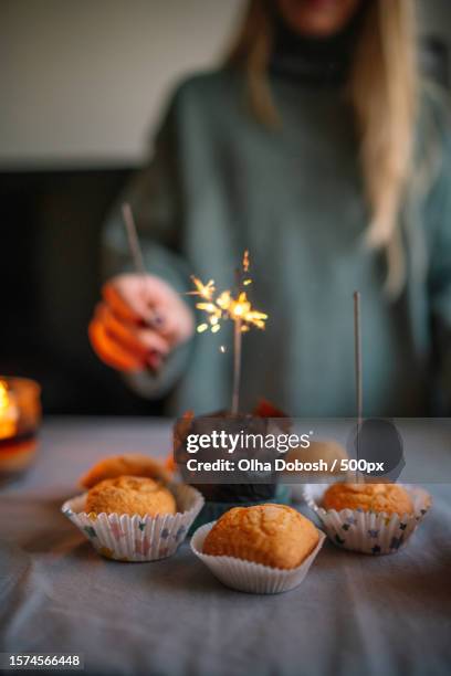 close-up of woman holding lighter to spark sparklers for cupcakes at home in dark room,spain - lighter spark stock pictures, royalty-free photos & images