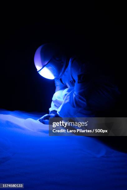 side view of male astronaut standing on illuminated blue light against black background,monahans,texas,united states,usa - space helmet stock pictures, royalty-free photos & images