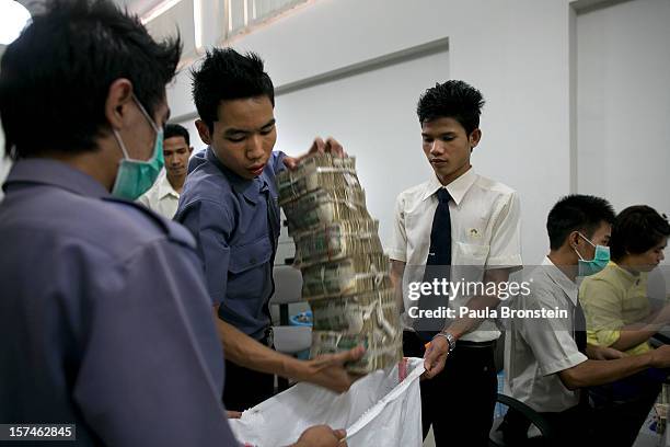 Burmese Kyat is put into a money bag after being counted at a bank November 30, 2012 in downtown Yangon, Myanmar. Burmese kyat is now available at...