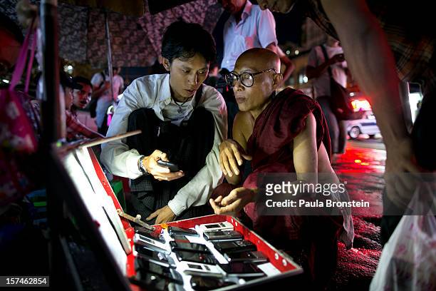 Burmese monk shops for a used mobile phone at a street market November 30, 2012 in Yangon, Myanmar. Business is booming in this newly opened...