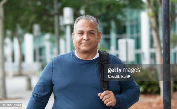 reifer hispanischer mann, der rucksack in der stadt trägt - chubby men stock-fotos und bilder
