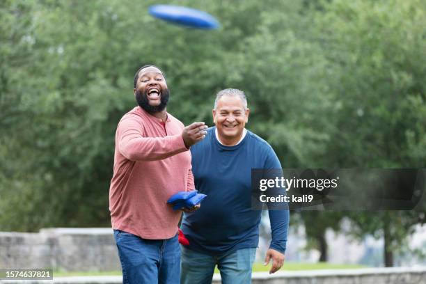 two heavyset multiracial men playing bean bag toss - corn hole stock pictures, royalty-free photos & images