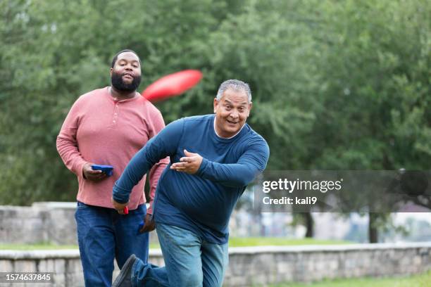 two heavyset multiracial men playing bean bag toss - playing corn hole stock pictures, royalty-free photos & images