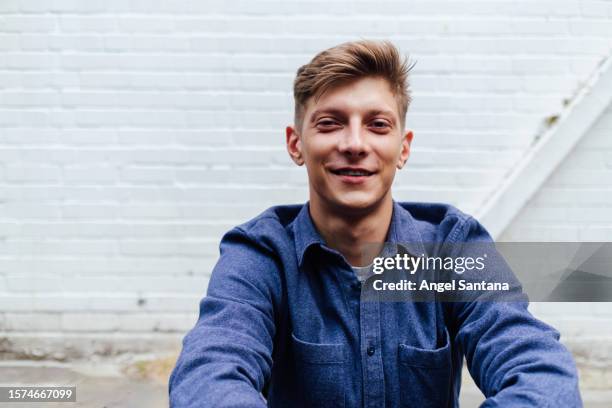 portrait of a young man on white brick wall - outisde stock pictures, royalty-free photos & images