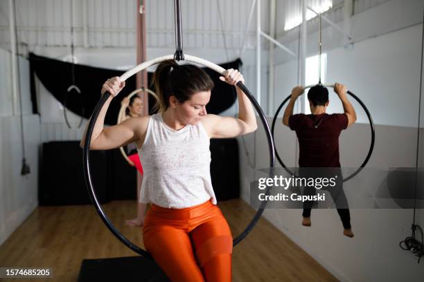 people sitting on a lyra hoop during aerial gymnastics class - lyra stock pictures, royalty-free photos & images