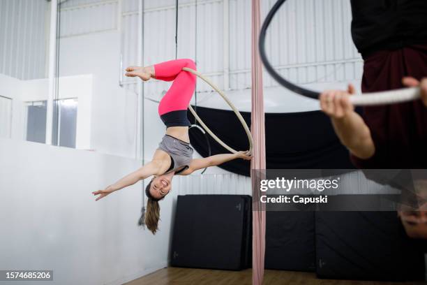 smiling woman on a lyra hoop during gymnastics class - lyra stock pictures, royalty-free photos & images