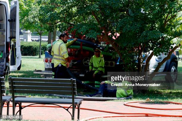 Construction workers rest in the shade during maintenance work in Lafayette Park on July 27, 2023 in Washington, DC. Washington DC is under an...