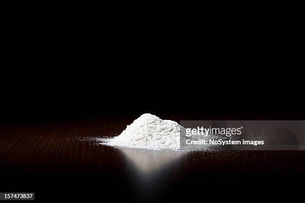 a small pile of white powder on a dark surface - heroïne stockfoto's en -beelden