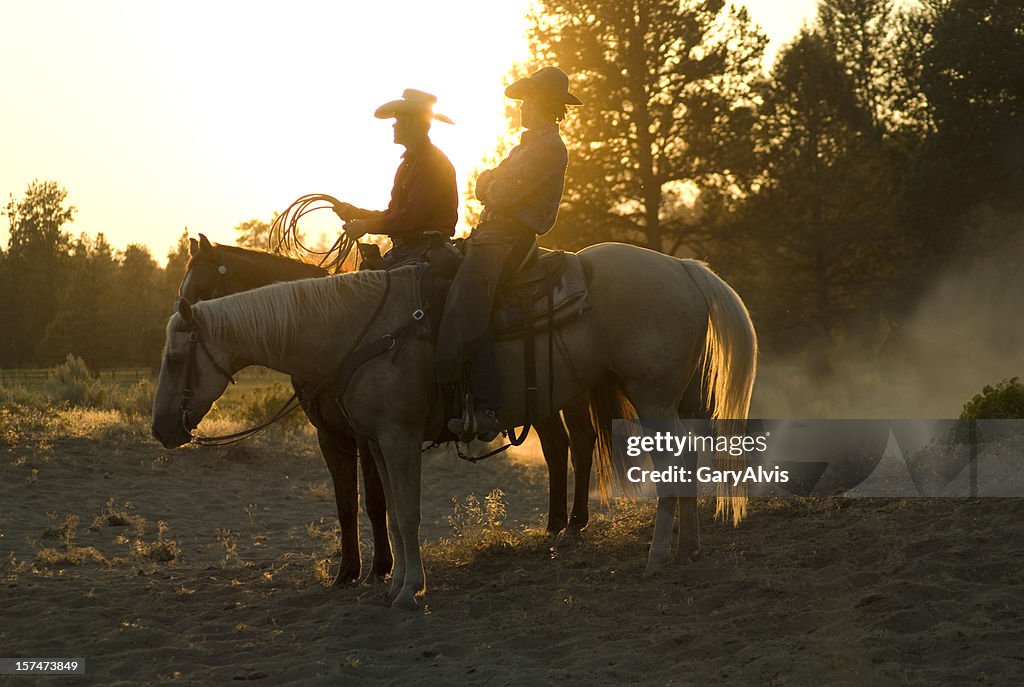 Zwei cowboys sitzt auf der Pferde bei Sonnenuntergang