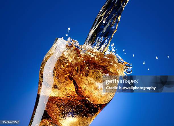 cola com um grande splash, isolado no azul - soda imagens e fotografias de stock