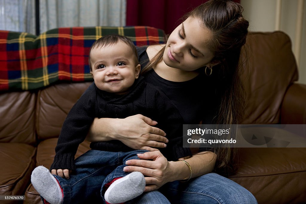 Adorable Baby Boy Sitting on Latina Mother's Lap at Home