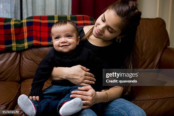 adorable baby boy sitting on latina mother's lap at home - council flats stock pictures, royalty-free photos & images