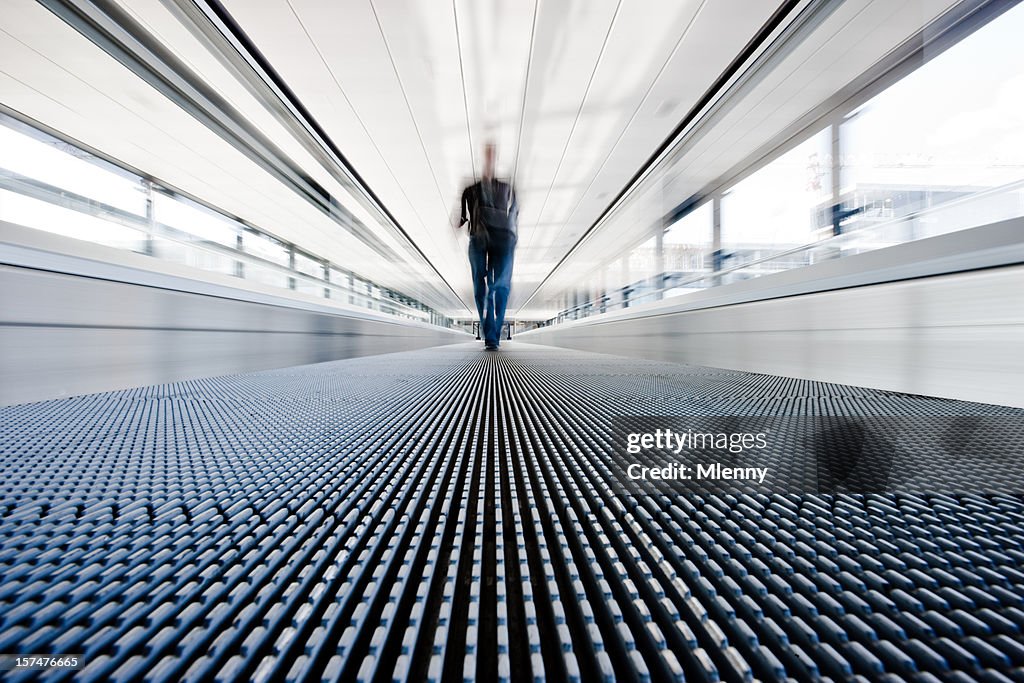 Traveller walking on moving stairway airport walkway