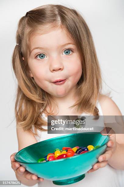 petite fille tenant un bol avec du sucre dans la bouche. - confiserie photos et images de collection