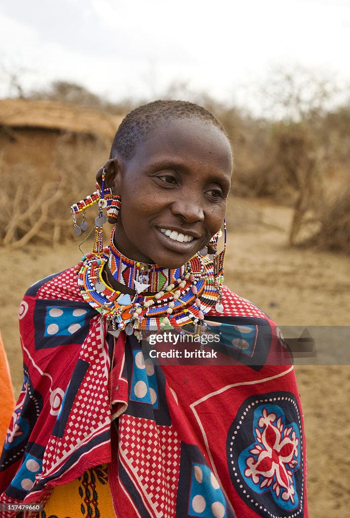 Young smiling Masai woman in front of her village, Kenya.