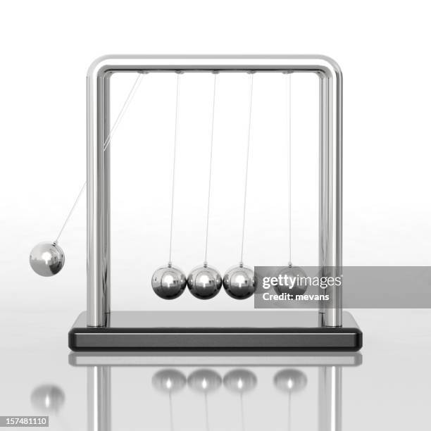 newton's cradle sitting on a reflective desk - newtons cradle stockfoto's en -beelden