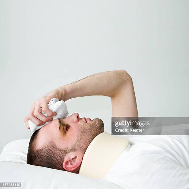 injured young man with neck collar placing ice on his head - plooikraag stockfoto's en -beelden