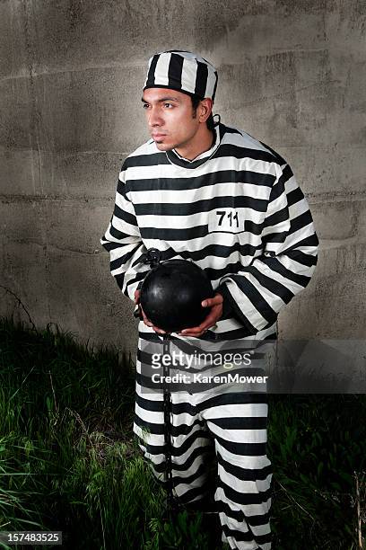 prisoner in black and white stripes holding a ball & chain - gevangene stockfoto's en -beelden