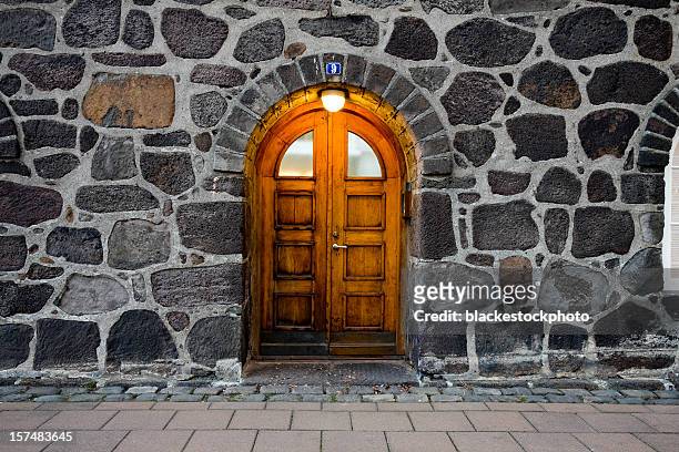 wooden door in illuminated doorway, set within stone wall - castle background stock pictures, royalty-free photos & images
