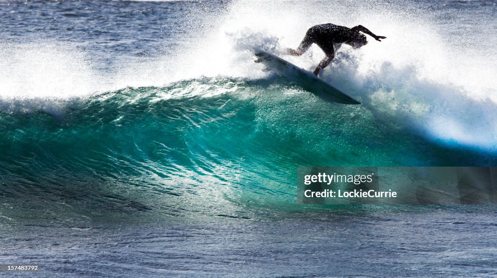 A surfer tries to stay on the surfboard while riding a wave