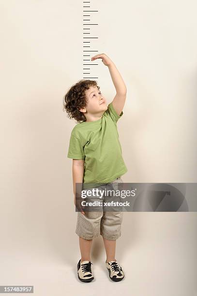 small child measuring himself standing up - lengte stockfoto's en -beelden