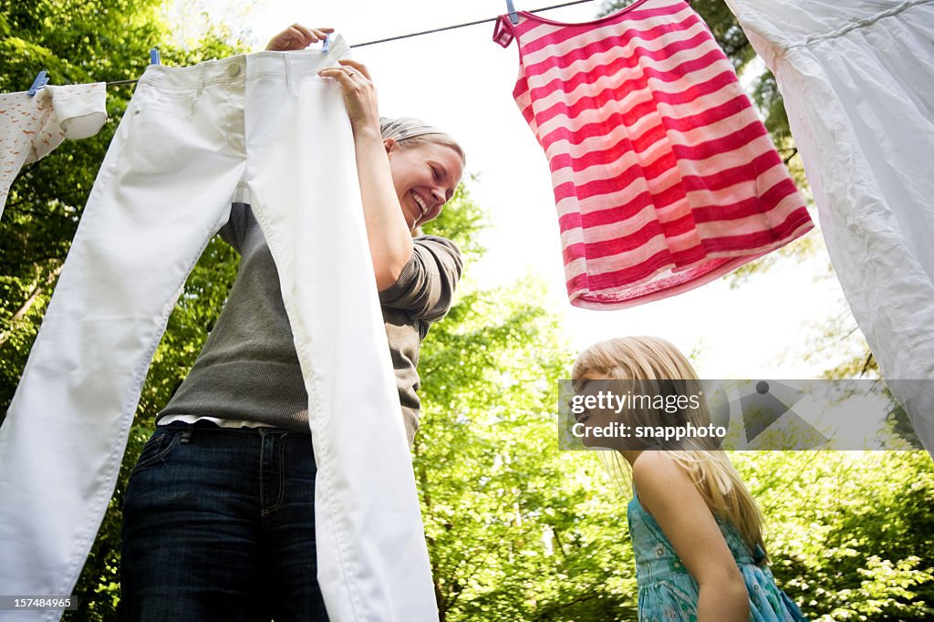 Smiling mother and child hanging clothes outside together