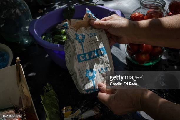 Lilia Martyniuk shows off an old bag of salt mined from Soledar, which is now under Russian occupation, as she prepares tomatoes for pickling in her...