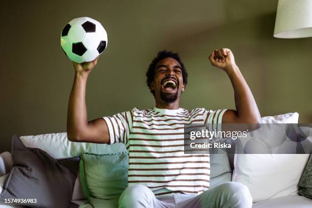 live action entertainment: young man enjoys soccer match on tv - match final stock pictures, royalty-free photos & images