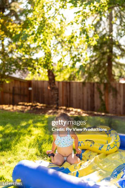 happy toddler girl playing on a slip n' slide - hot american girl stock pictures, royalty-free photos & images