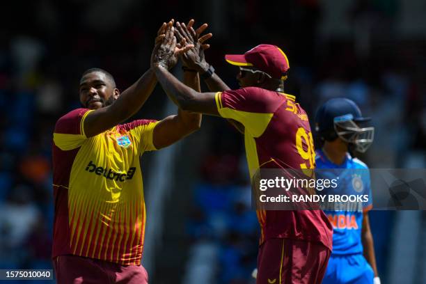Obed McCoy and Jason Holder of West Indies celebrate the dismissal of Axar Patel of India during the first T20I match between West Indies and India...