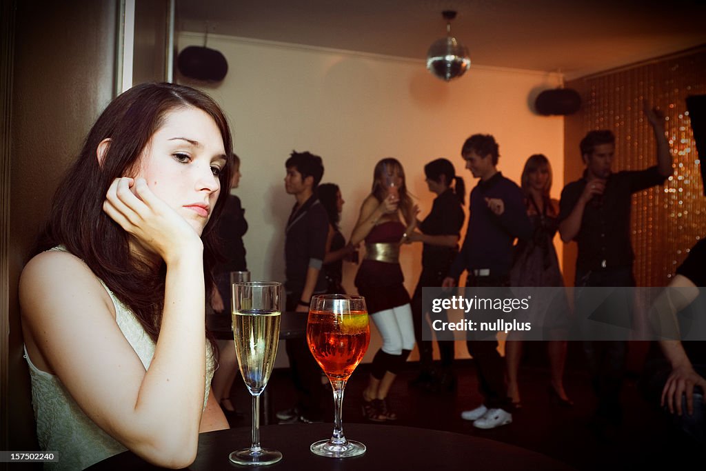 Joven mujer está sentado solo en un club nocturno