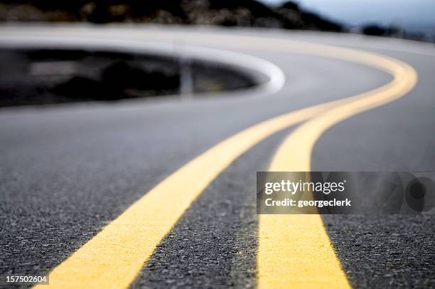 gelbe linien auf eine kurvenreiche straße - road stock-fotos und bilder