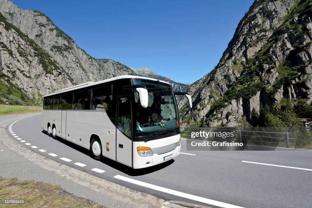 Blue sky over white bus crossing the alpes